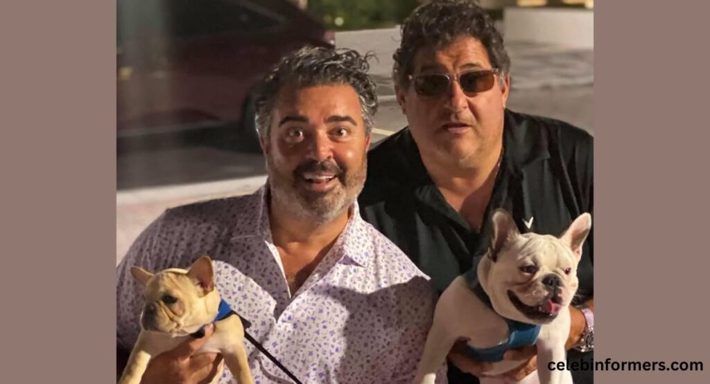 Two men, each holding a dog, smile happily for the camera, capturing a delightful moment of camaraderie.